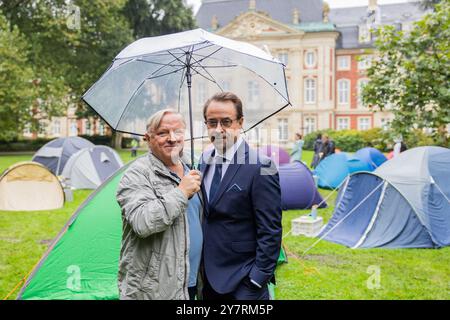 PRODUCTION - 01 octobre 2024, Rhénanie-du-Nord-Westphalie, Münster : Axel Prahl (inspecteur en chef Frank Thiel, l), acteur, et Jan Josef Liefers (professeur Karl-Friedrich Boerne), acteur, se tiennent entre des tentes dans le parc derrière le château sur le plateau du Münster 'Tatort'. Le nouvel épisode 'je confesse' (AT) traite de la pénurie de logements chez les étudiants. Photo : Rolf Vennenbernd/dpa Banque D'Images