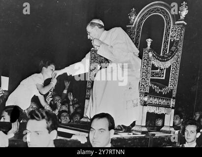 LE PAPE BÉNIT LES ENFANTS beaucoup d'enfants étaient dans la grande foule de pèlerins reçus en audience à l'occasion de Pierre par le Pape cette semaine avant qu'il ne quitte Rome pour son palais d'été à Castelgandolfo. La photo montre Un jeune garçon est soulevé de la foule par ses parents pour embrasser l'anneau sur le doigt du pape Pie XII. 15 juillet 1953 Banque D'Images