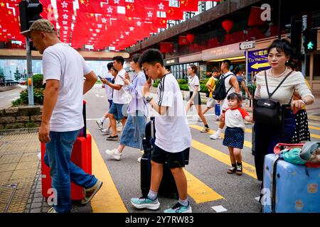 Hong Kong, Hong Kong. 1er octobre 2024. Les touristes ont vu traverser une toile de fond des drapeaux de Chine et de Hong Kong à Tsim Sha Tsui, Hong Kong. Hong Kong marque le 75e anniversaire de la fondation de la Chine. Crédit : SOPA images Limited/Alamy Live News Banque D'Images