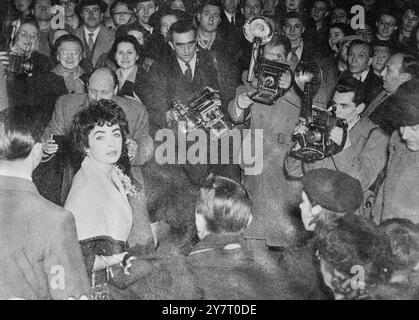 DES CAMÉRAS ET DES FOULES ENTOURENT ELIZABETH TAYLOR 20-2-52 . PHOTOS MONTRE:- Elizabeth Taylor, actrice britannique qui est arrivée d'Amérique hier soir pour son mariage avec l'acteur britannique Michael Wilding, demain à Londres, vue entourée d'une batterie de caméras et d'une foule d'admirateurs quand elle est sortie de son hôtel londonien aujourd'hui 20 février 1952 Banque D'Images