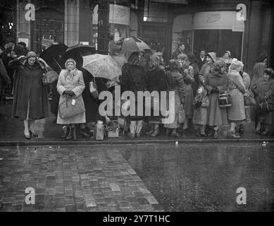 ILS ATTENDENT SOUS LA PLUIE LE CORTÈGE FUNÉRAIRE DE KING 11-2-52 EXPOSITIONS DE PHOTOS :- les parapluies et les mackintoshes étaient beaucoup en usage par les gens qui ont tracé la route pour le cortège funéraire du roi à travers Londres jusqu'à Westminster Hall aujourd'hui. Voici une scène à l'extérieur de Kings Cross Station, où le cercueil arrivait de Wolferton Station.;foule le 11 février 1952 Banque D'Images