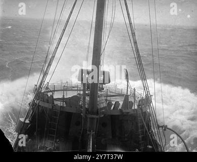 CONVOI D'HIVER ces photos ont été prises à bord d'un navire d'escorte qui accompagnait un convoi apportant de la nourriture du monde extérieur et des fournitures de port en port à travers des mers d'hiver rendues dangereuses par les mines et les sous-marins, le ciel au-dessus d'une menace constante des avions de guerre allemands. Le temps était mauvais. Le spray a gelé sur les vêtements et les visages des artilleurs et des hommes qui regardaient. Les mers battent contre ces petits navires. Ils ont apporté leur cargaison. La photo montre : une charge de profondeur étant soigneusement chargée à l'arrière. 23 décembre 1940 Banque D'Images