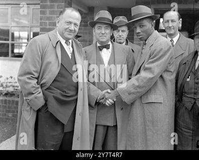 [ Légende originale ] - ACCUEIL DE L'AÉROPORT - JACK SOLOMENS (à droite ) salue LE SELLIER DE SABLE , boxeur qui a tenu pendant quatre mois le championnat du monde des poids plume , à son arrivée par Pan American '' Clipper '' à l'aéroport de Londres . - Saddler affrontera JIM KEERY , poids léger irlandais , à la White City , Londres , le 2 juin , dans le programme du championnat Woodcock - Mills . - 24 mai 1949 Banque D'Images