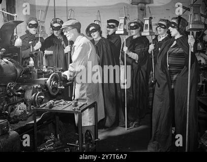 NOELS SUR LE QUART DE NUIT L'esprit de Noël a apporté à l'âge de la machine alors que les carollers masqués chantent pour M. J George Jackson, un travailleur de nuit dans une usine d'ingénierie de Wolverhampton. Les chanteuses, qui collectent des fonds pour des œuvres caritatives locales, sont membres de la Wolverhampton Round table et du Ladies' Circle. 18 décembre 1950 Banque D'Images