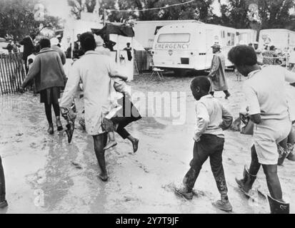 WASHOUT WASHINGTON : les militants des pauvres gens fuyant la ville de la Résurrection ici après de fortes pluies ont transformé leur camp en bourbier. Une mère porte son enfant dans un bras et ses chaussures dans l'autre alors qu'elle marche dans la boue. 24 mai 1968 Banque D'Images