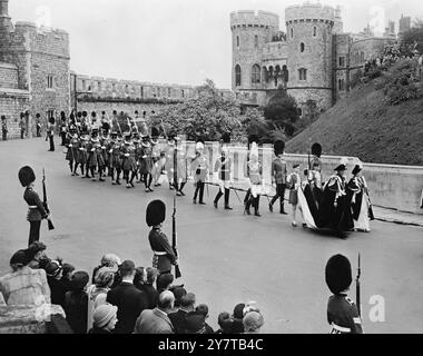 ROI ET REINE EN PROCESSION BRILLANTE DE LA JARRETIÈRE - - 27 avril 1950 - - leurs brillants manteaux de velours bleu kingfisher arborés d'un badge et d'une devise faisant une éclat de couleur vive contre les murs grisés du château de Windsor, le roi et la reine ont marché aujourd'hui (jeudi) en procession jusqu'à la chapelle Georges pour assister au service du très noble ordre de la jarretière, premier ordre de la chevalerie britannique. - À l'intérieur de la chapelle, les stalles surplombées des bannières flamboyantes des Chevaliers, de la princesse Margaret, des duchesses de Gloucester et de Kent regardaient le service depuis des sièges spéciaux dans le chœur. - Banque D'Images