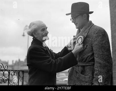 90 ET IL se BAT TOUJOURS CONTRE LES ÉLECTIONS du 20 février 1950 bien qu'il ait 90 ans, un coin de feu confortable et un fauteuil profond n'attirent pas M. Edwin Thomas Butteriss lorsqu'il y a une élection à disputer. Ce courageux vétéran qui a participé à sa première élection il y a 76 ans lorsque Gladstone a été battu à Greenwich, est en tournée dans la division Heston et Isleworth (Middlesex) pour soutenir M. R Reader Harris, le candidat conservateur. Image montre : M. Edwin Thomas Butteriss fixe la rosette pour M. R Reader Harris, candidat conservateur, devant une sollicitation dans la division Heston et Isleworth aujourd'hui (Mond Banque D'Images