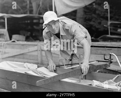 LES RAMEURS D'ANGLETERRE ENTRAVÉS PAR LA PERTE D'ÉQUIPEMENT. Mike LePage, NO.7 dans les England Eights, centrant l'équipement de gréement sur la coque de l'équipe avant un entraînement final à Lake, Karapiro, Nouvelle-Zélande, pour les matchs de l'Empire. L'équipage de l'Angleterre - qui a ramé 3e à l'Australie et la Nouvelle-Zélande dans les jeux - a été entravé dans l'entraînement final par la perte des gréeurs pour leur coquille, qui a été envoyé d'Angleterre. L'avion a atterri du ' Tongariro ' à Auckland quelques jours avant l'ouverture des jeux, mais il n'a pas été possible de trouver un boîtier distinct contenant les gréeurs. Pour la formation dans leur propre coquille, ils transfèrent Banque D'Images