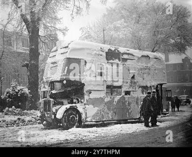 Huit à l'hôpital après l'accident d'autobus de Londres dans la neige neige s'accrochant au côté d'un autobus de transport de Londres No 93 dans lequel un certain nombre de personnes ont été blessées sur Wimbledon Hill , Londres. L'autobus , qui a dérapé et s'est renversé sur la chaussée enneigée, glacée et gélifiée , est photographié après avoir été remis sur ses roues par des dépanneurs. 2 janvier 1951 Banque D'Images