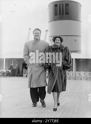 Southampton : L'acteur Van Johnson , avec son col de manteau retourné pour se protéger contre le vent fort , se promène sur le pont du paquebot Queen Elizabeth avec sa femme. Il retourne en Amérique après avoir assisté à la première de son film ' Battleground ' au Théâtre Empire du .22 mars 1950 Banque D'Images