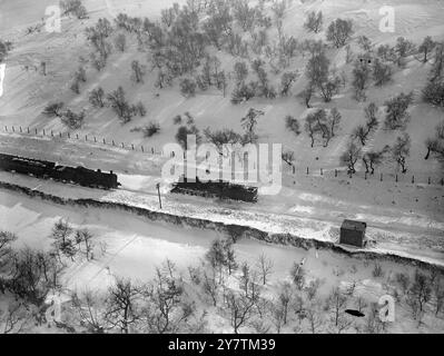 Photo aérienne - les trains ont neigé après un grand blizzard dans les montagnes galloises alors que d'énormes déneigements bloquent les lignes. D'énormes enneigements ont bloqué les routes et les chemins de fer dans tout le pays et il n'y a pratiquement aucun mouvement sur les chemins de fer dans les vallées galloises. Les gisements houillers sont gravement touchés. Photo montre : une photographie prise depuis les airs montrant des trains neigés , et immobiles , sur la ligne Abergavenny - Merthyr au pays de Galles le 7 mars 1947 Banque D'Images