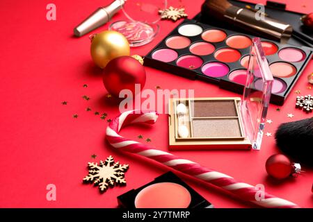 Produits de maquillage et décor de Noël sur fond rouge, gros plan Banque D'Images