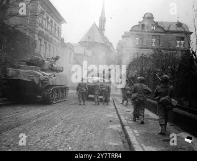 Combats de rue en GermanyLes spectacles de photos : infanterie suivre les chars de fer de lance de la 11ème division blindée, 3ème armée américaine dans Andernach, Allemagne. Un tireur d'élite tire sur les troupes depuis le bâtiment de gauche , et un infanterie derrière le char de tête l'a repéré le 14 mars 1945 Banque D'Images