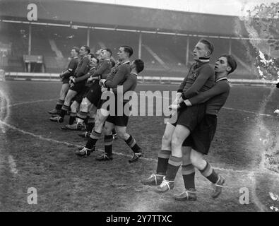 PORTANT TOUT DEVANT EUX - L'ÉQUIPE BELGE DE FOOTBALL VA S'ENTRAÎNER AU WHITE CITYL'équipe belge de football de l'Association nouvellement arrivée dans ce pays pour jouer contre une équipe d'Angleterre à Wembley le 19 janvier, a été entrée dans un entraînement rigoureux au White City Stadium. Sauter grenouille, ramasser un dos, et les exercices de portage de poids sont parmi les secousses physiques qui maintiennent ces jeunes hommes dans le rose de condition pour leurs prochains concours. Après leur match contre l'Angleterre, les Belges rencontreront une équipe écossaise à Hampden Park, Glasgow le 23 janvier. Photos montre : la voiture de l'équipe belge Banque D'Images