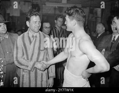 WOODCOCK ET LESNEVICH PESENT EN Bruce Woodcock, champion britannique des poids lourds et Gus Lesnevich, détenteur américain du titre mondial des poids lourds, pesent au gymnase Jack Solomons dans le West End pour leur combat en dix manches à Harringay ce soir (mardi). La photo montre : Lesnevich (à gauche) et Woodcock serrant la main à la pesée. 17 septembre 1946 Banque D'Images