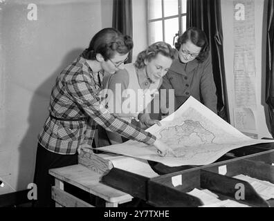 DES FEMMES POUR CONTRÔLER LA PLUS GRANDE COLLECTE DE FERRAILLE EN ANGLETERRE trois femmes partiront de Londres pour commencer la plus grande collecte de ferraille de l'histoire. Ces femmes - officiellement appelées assistants chargés des travaux d'urgence - superviseront chacune une équipe de 10 assistantes chargées de veiller à ce que 40 000 tonnes de ferraille soient envoyées chaque semaine dans les fours de fusion pour être transformées en armes de guerre. Photos : Mme d Ross, Mme lance Sieveking et Mlle Papineu étudient une carte des premières zones à être couvertes dans la grande campagne de sauvetage, à leur siège londonien. 14 janvier 1942 Banque D'Images