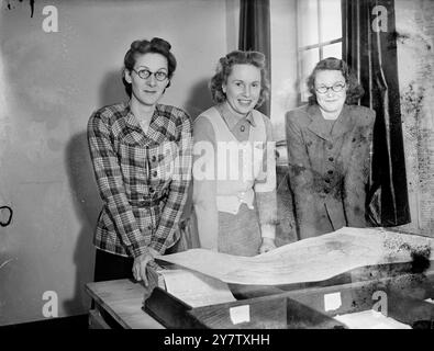 DES FEMMES POUR CONTRÔLER LA PLUS GRANDE COLLECTE DE FERRAILLE EN ANGLETERRE trois femmes partiront de Londres pour commencer la plus grande collection de ferraille de l'histoire. Ces femmes - officiellement appelées assistants chargés des travaux d'urgence - superviseront chacune une équipe de 10 assistantes chargées de veiller à ce que 40 000 tonnes de ferraille soient envoyées chaque semaine dans les fours de fusion pour être transformées en armes de guerre. Photos : Mme d Ross, Mme lance Sieveking et Mlle Papineau étudient une carte des premières zones à être couvertes dans la grande campagne de sauvetage, à leur siège de Londres. 14 janvier 1942 Banque D'Images