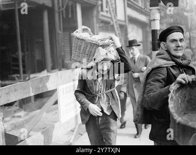 LONDRES EN TEMPS DE GUERRE - TRAVAILLEURS DE DÉMOLITION le travail de nettoyage de Londres des ruines de ses bâtiments endommagés par la bombe continue après près de huit mois de libération des raids aériens. C'est une scène typique de Londres en temps de guerre - et deux ouvriers de démolition typiques. Le vieil homme à gauche est Charles Dolan âgé de 59 ans. Il transporte une bâche de briques d'un bâtiment détruit. 1941 Banque D'Images