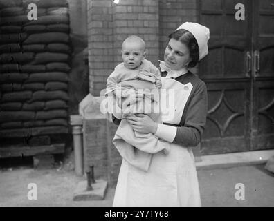 BÉBÉ DE DIX MOIS RETROUVÉ ABANDONNÉ DANS UNE CABINE TÉLÉPHONIQUE Un petit garçon de dix mois a été retrouvé abandonné dans une cabine téléphonique à Norbiton enveloppé dans un mackintosh de dame. Le bébé a les cheveux clairs, le teint frais, de grands yeux gris et a été bien soigné. Il est maintenant pris en charge à la Central relief institution, Norbiton, surrey. Photos montre : le bébé garçon dans les bras d'une sœur à l'institution. 12 février 1941 Banque D'Images