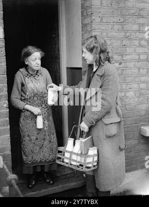 Le Milkwoman DE LONDRES, 15 ANS, Rose Brown, 15 ANS, de Marcia Road, Walworth, a pris la place d'un laitier appelé par les Forces. Chaque matin, à 8 heures, Rose commence sa tournée en poussant une étable à lait lourdement chargée. À 14 heures, elle termine et retourne à la laiterie pour donner un coup de main dans le département de mise en bouteille jusqu'à 17 heures. Elle s'est portée volontaire pour le travail lorsque le laitier a été appelé et personne d'autre n'a pu être trouvé pour prendre le travail. Photo montre : Rose Brown livrant du lait à la porte. 8 février 1941 Banque D'Images