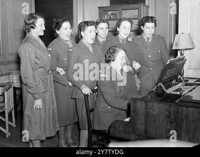 CHANSON DE LA FRANCE LIBRE le corps Feminin (l'homologue français libre de l'ATS) est maintenant à la hauteur - avec son siège à Londres. Ici, les filles ont leur propre cantine, et sont en mesure de passer leurs heures de repos ensemble, avec des jeux, du chant et d'autres commodités et compagnie. Spectacles de photos : des filles heureuses du corps Feminin chantant autour d'un piano à leur quartier général à Londres. 1er février 1941 Banque D'Images
