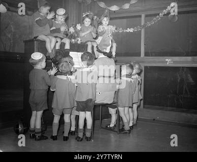 Une FÊTE DE NOËL - LA GARDERIE TOTTENHAM les enfants dans une garderie pour enfants de moins de cinq ans, dont les pères sont principalement dans l'armée et dont les mères travaillent, ont néanmoins eu un chirstme agréable. Spectacles de photos : les enfants debout autour du piano et certains même assis sur le dessus, appréciant une chanson chantée. 18 décembre 1940 Banque D'Images