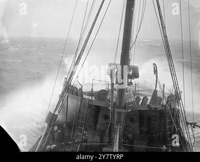 CONVOI D'HIVER ces photos ont été prises à bord d'un navire d'escorte qui accompagnait un convoi apportant de la nourriture du monde extérieur et des fournitures de port en port à travers des mers d'hiver rendues dangereuses par les mines et les sous-marins, le ciel au-dessus d'une menace constante des avions de guerre allemands. Le temps était mauvais. Le spray a gelé sur les vêtements et les visages des artilleurs et des hommes qui regardaient. Les mers battent contre ces petits navires. Ils ont apporté leur cargaison. La photo montre : une charge de profondeur étant soigneusement chargée à l'arrière. 23 décembre 1940 Banque D'Images