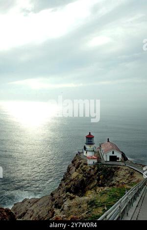 Point Reyes, Calif.,-- les phares de point Reyes vieux de 132 ans se sont accrochés à la mer battue comme il a été exposé au brouillard, au vent et au soleil alors que la balise et la corne de brouillard avertissent les mers. La lentille originale du phare a été conçue en 1823 par un ingénieur français désenchanté, Augustine Fresnel. Outre l'utilisation maritime, son invention qui concentrait la lumière rayonnante dans un faisceau horizontal, a été construite en 1870. Vingt-quatre panneaux verticaux dans la lentille grossissent la lumière à travers 1 032 prismes de cristal. Les rideaux sont fermés autour de la lentille chaque jour pour empêcher les rayons du soleil de commencer f Banque D'Images