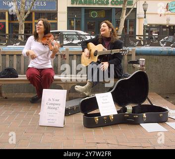 Palo Alto, Californie,--(de gauche à droite) Valarie Price, ingénieur logiciel licencié de Belmont, Calif., et Beneta Kenn, responsable des relations publiques high-tech licencié de Menlo Park, Californie, qui accueille maintenant des passants sur University Avenue au centre-ville de Palo Alto avec de la musique celtique et des CV. Ils espéraient attirer l'attention des cadres de haute technologie qui allaient déjeuner. Donc, le tarif n'offre pas d'emploi, mais il vaut mieux que le réglage à la maison en attendant que le téléphone sonne. Ils ont rencontré d'autres chômeurs qui aident leurs esprits. Photo prise le vendredi 15 février 2002 ) Banque D'Images