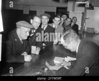 MOBILISER LES CONSTRUCTEURS tous les hommes âgés de 18 à 60 ans qui étaient autrefois employés dans les industries du bâtiment et du génie civil doivent maintenant s'inscrire aux bourses de l'emploi dans toute la Grande-Bretagne. Photos : M. H. Mackenzie de Peckham, maintenant messager au ministère de la production aéronautique et ancien ouvrier, s'inscrit avec d'autres hommes à la bourse de l'emploi de Westminster (Londres) le 16 juin 1945 Banque D'Images