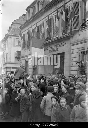 LA LIBÉRATION DE COLMAR Un grand accueil a été réservé aux hommes de la 28e division d'infanterie américaine et de la 5e division blindée française lorsqu'ils sont entrés dans Colmar, troisième ville d'Alsace, scellant ainsi virtuellement le sort de la 19e armée allemande encore dans la « poche » de Colmar. Photos : les habitants de Colmar attendent d'accueillir les troupes alliées. En arrière-plan, le bulding balisé est la Stadthauptkasse, ou banque principale de Colmar. 7 février 1945 Banque D'Images