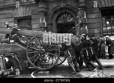 Un incendie a éclaté ce matin dans le sous-sol du War Office, dans une pièce utilisée pour entreposer de la papeterie. Les pompiers portaient un appareil respiratoire spécial lorsqu'ils entraient dans le bâtiment rempli de fumée pour faire face à l'incendie. Photos : pompiers au travail sur leur moteur au War Office ce matin. 12 juillet 1950 Banque D'Images