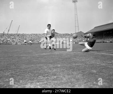 Le gardien de Manchester United David Gaskell grimaces alors qu'il plonge pour sauver ce tir d'attaquer Fulham à droite Johnny Key (à gauche) pendant le match ici aujourd'hui . En arrière-plan, le dos gauche de Manchester United Tony Dunne. Fulham remporte le match le 2-1 .5 septembre 1964 Banque D'Images