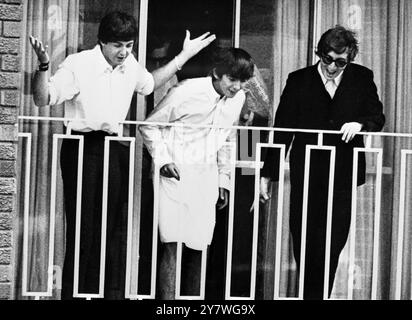 Les Beatles - Paul McCartney , George Harrison et John Lennon sur le balcon de leur hôtel accueillent une foule de fans après leur arrivée à Sydney, Australie le 14 juin 1964 Banque D'Images