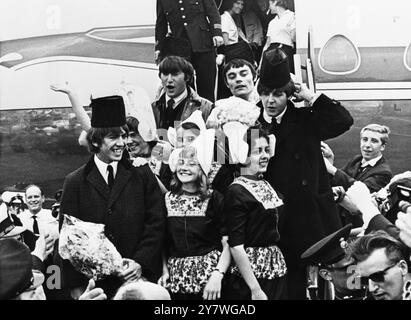 Les Beatles à l'aéroport de Schiphol , Amsterdam avec des filles hollandaises en costume national . George Harrison ( à gauche ) , John Lennon ( au centre à gauche ) Jimmy Nicols (au centre à droite - batteur remplaçant de Ringo Starr qui est malade ) et Paul McCartney . 5 juin 1964 Banque D'Images