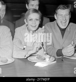 Le mannequin Twiggy se glisse dans une pomme de terre en veste préférée par le boxeur Billy Walker ( à gauche ) dans une assiette tenue par le capitaine d'Arsenal, Terry Neal, lors de la première séance de patates en veste à midi au Flamingo Club, Wardour Street, .28 décembre 1966 Banque D'Images