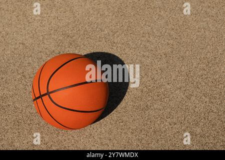 Ballon orange de basket-ball sur un terrain de sport coloré avec une ligne blanche. Équipement de sport sans personnes. Arrière-plan sport. Sport d'équipe. Copier l'espace. Vue de dessus Banque D'Images