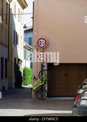 Mantoue, Italie 30 septembre 2024 Un vélo vert citron est appuyé contre un mur sous un panneau de limitation de hauteur et de vitesse dans une ville italienne Banque D'Images