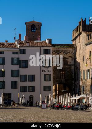 Mantoue, Italie 30 septembre 2024 touristes appréciant une journée ensoleillée assis aux tables d'un bar sur la place piazza castello avec la tour civique de Palaz Banque D'Images