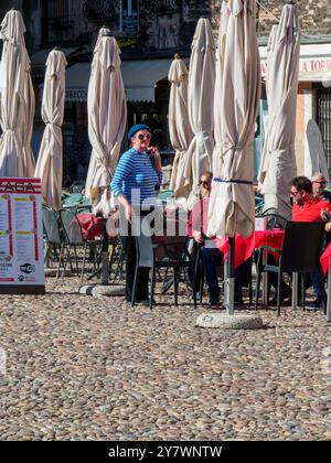 Mantoue, Italie 30 septembre 2024 les touristes marchent sur une place pavée avec des parasols fermés et un café en plein air à mantoue, lombardie, italie Banque D'Images