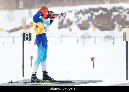 Athlète tirant en position debout au champ de tir dans une compétition de biathlon. Banque D'Images