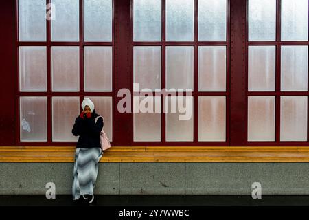 Jeune fille musulmane portant un foulard assis contre une fenêtre encore à la gare centrale, attendant son train de correspondance pour rentrer chez elle. Anvers, Belgique. Banque D'Images