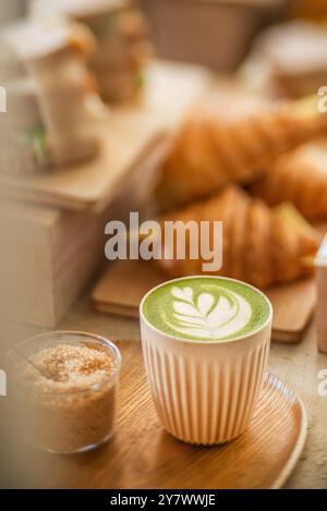 Tasse de matcha latte entourée de délicieuses pâtisseries, dans un café. Vue latérale. Latte crème Planche à découper en bois. Banque D'Images
