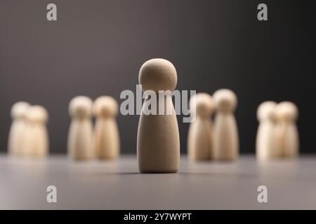 Concept de solitude. Figure humaine éloignée des autres sur fond gris Banque D'Images