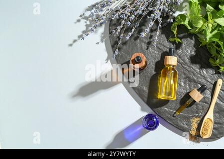 Teintures en bouteilles et herbes médicinales sur table blanche, vue de dessus. Espace pour le texte Banque D'Images