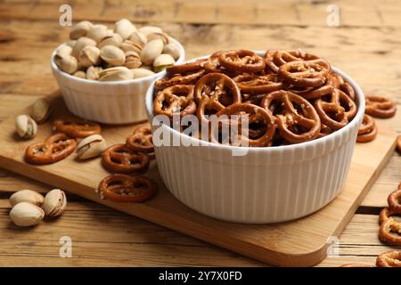 Délicieux bretzel craquelins et pistaches sur table en bois, gros plan Banque D'Images