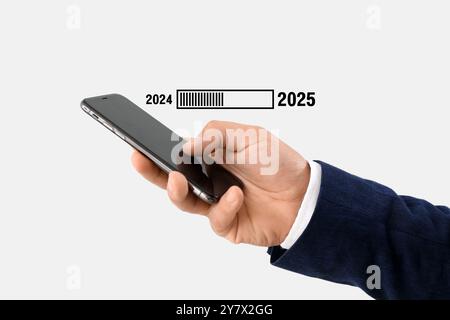 Main de l'homme d'affaires utilisant le téléphone portable et la barre d'état avec l'année 2024 et 2025 sur fond clair Banque D'Images