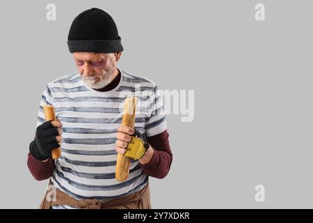 Homme sans-abri mature avec baguette sur fond clair Banque D'Images