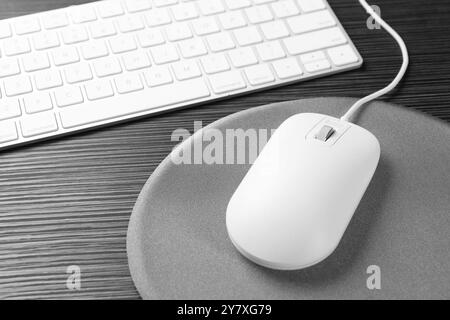 Souris d'ordinateur, tapis de souris et clavier sur table en bois noir Banque D'Images