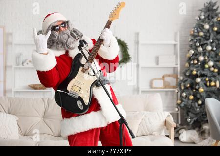 Cool Père Noël avec guitare et microphone chantant à la maison Banque D'Images